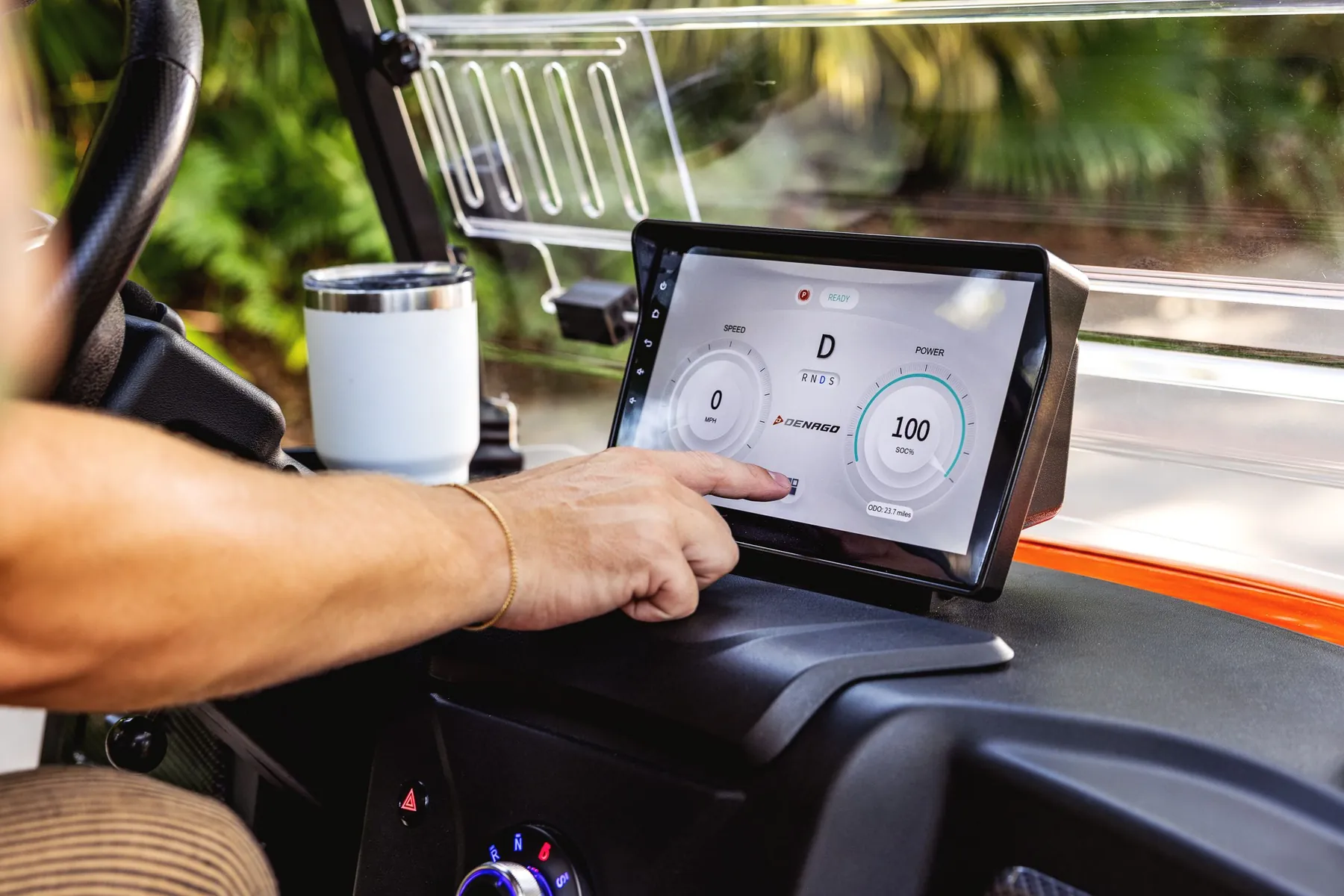 Driver using the touchscreen in a Denago golf cart